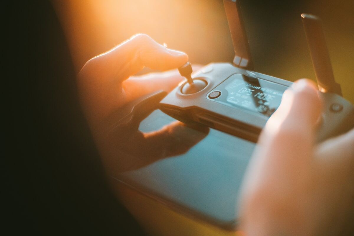 Mains manipulant un contrôleur de jeu électronique dans une lumière chaude.