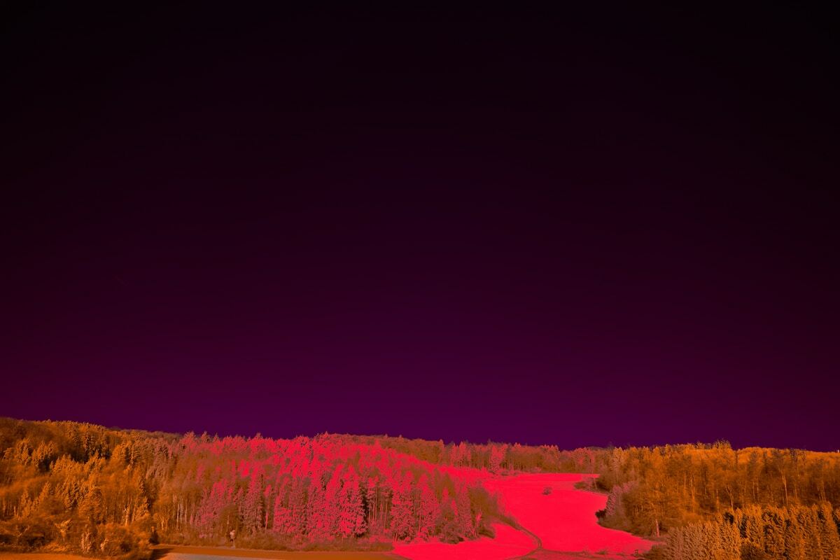 Paysage nocturne automnale avec forêt colorée et rivière rouge.