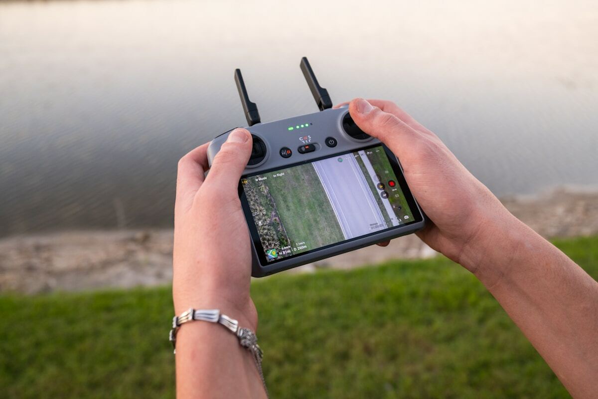Drone télécommandé avec écran affichant une vue aérienne d'un paysage.