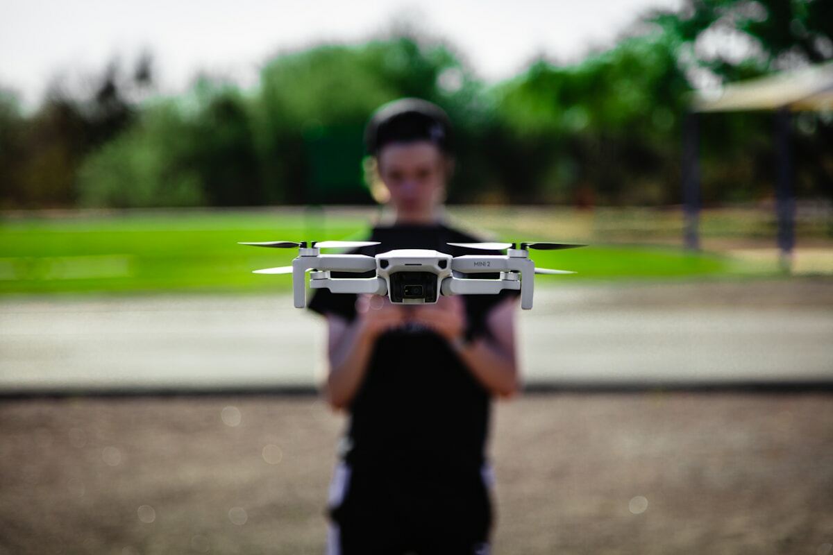 Personne tenant un drone quadrirotor dans un parc verdoyant.