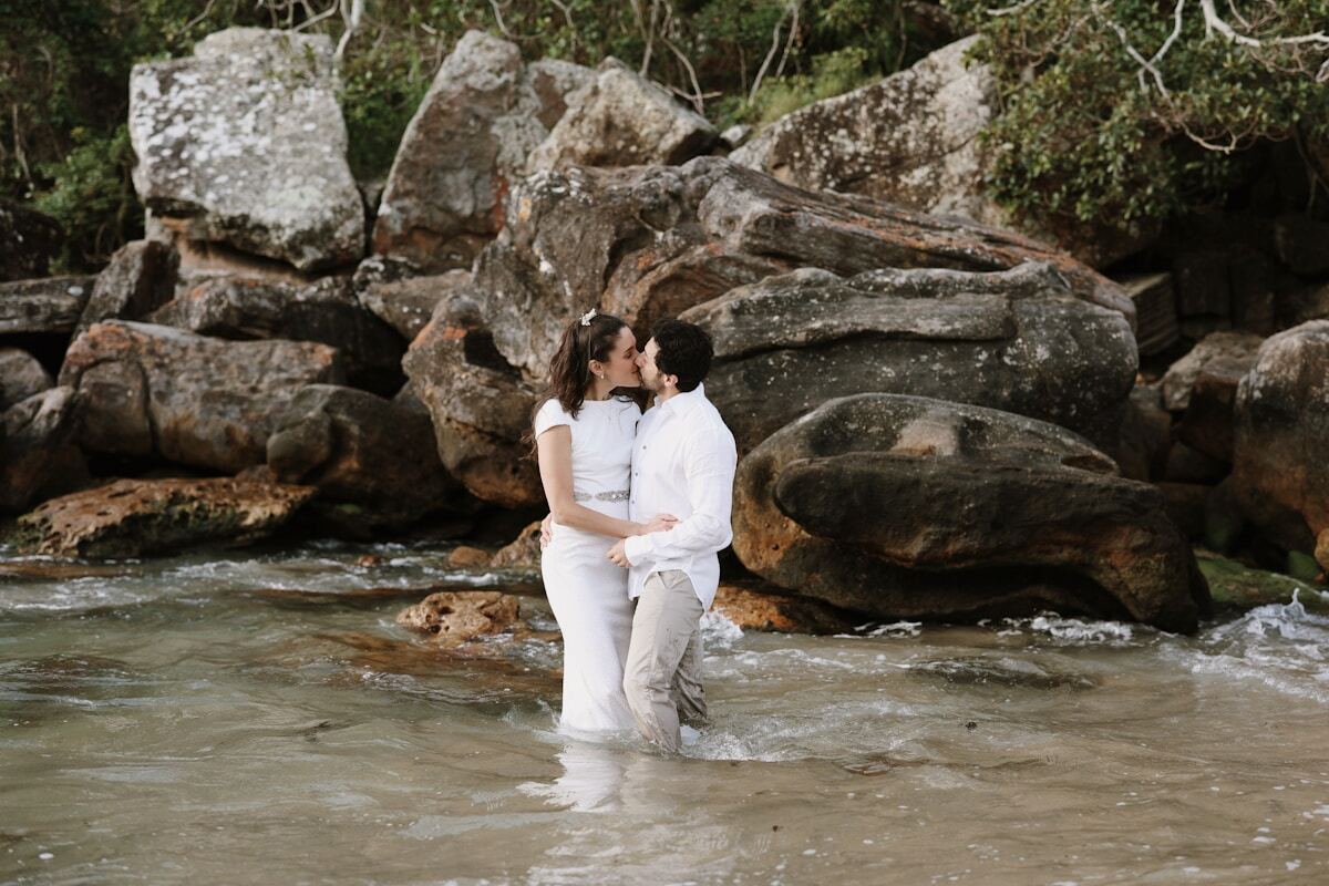 Couple amoureux s'embrassant dans un ruisseau entouré de rochers.