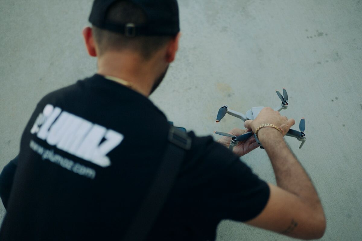 Homme en uniforme noir tenant un drone.