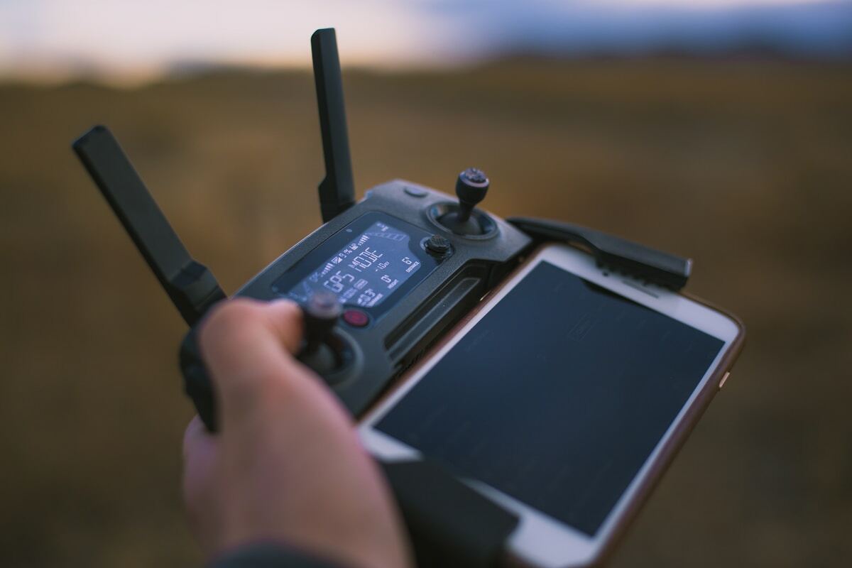 Drone télécommandé avec écran tactile dans un paysage naturel.