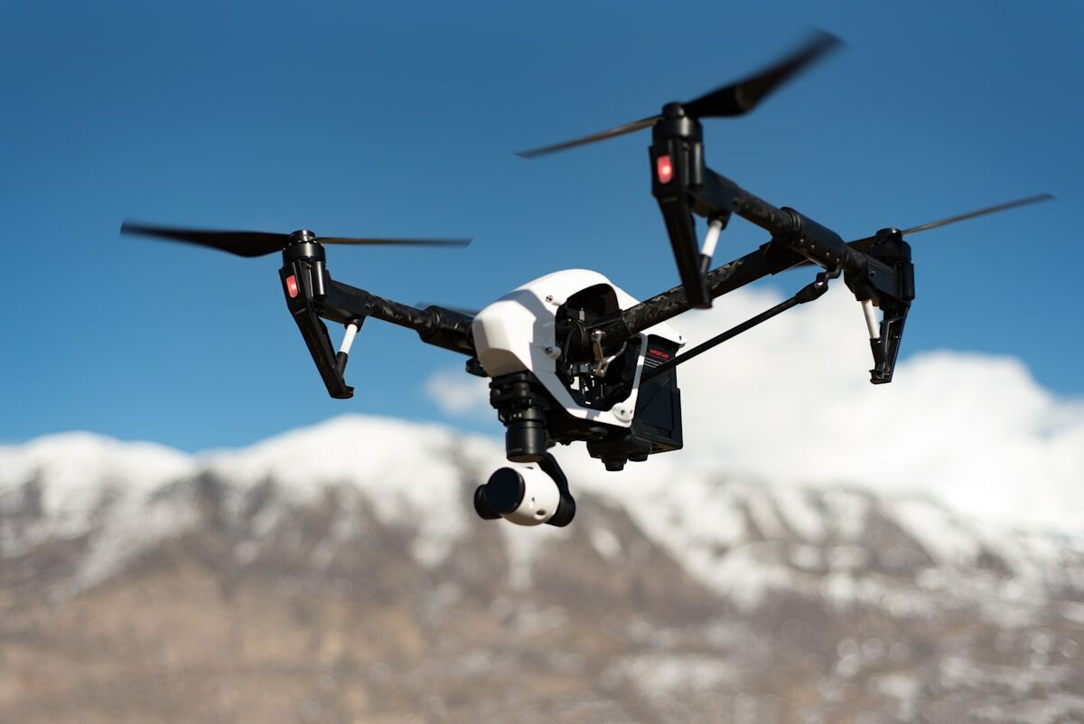 Drone volant avec caméra dans un paysage montagneux enneigé.