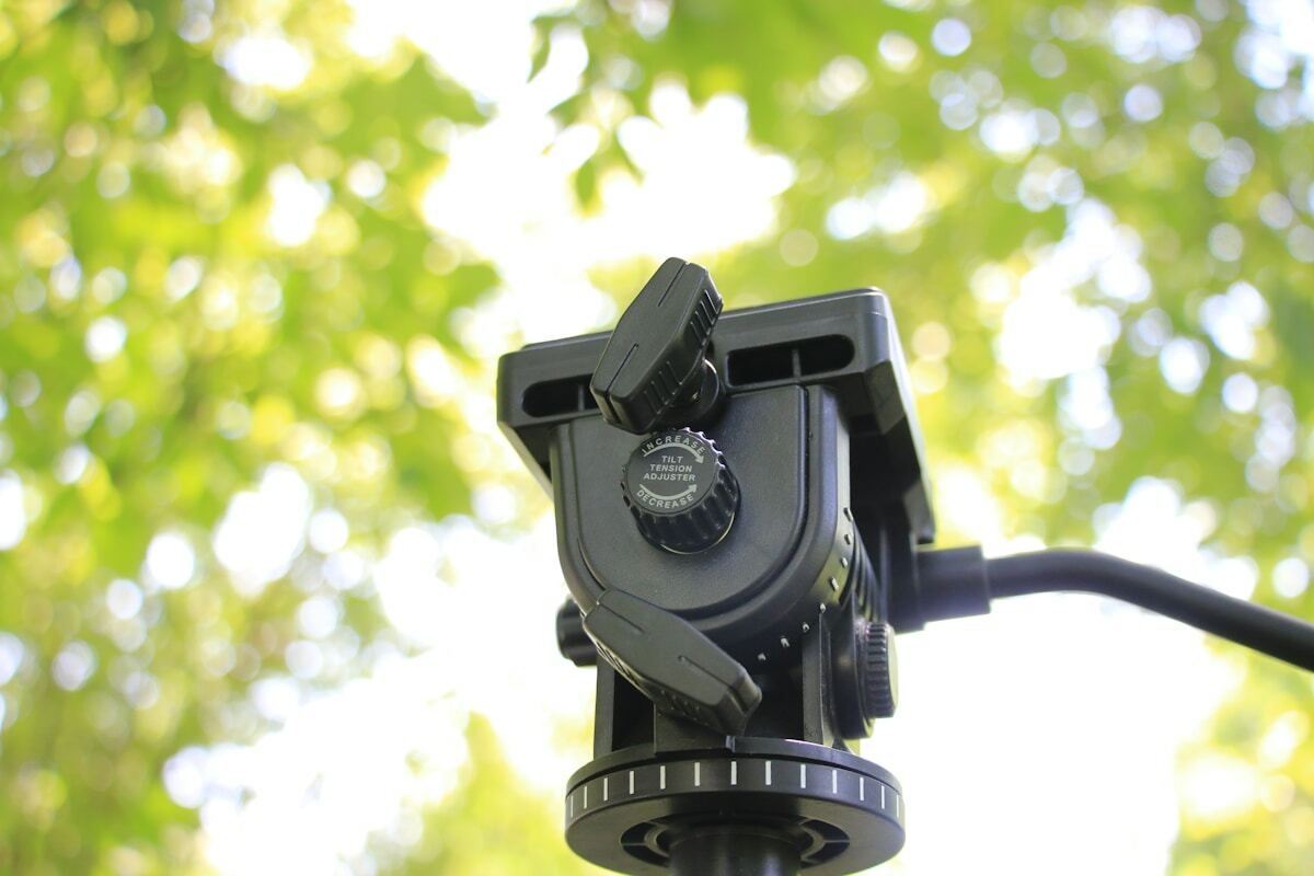 Caméra de photographie professionnelle sur trépied dans un environnement verdoyant.