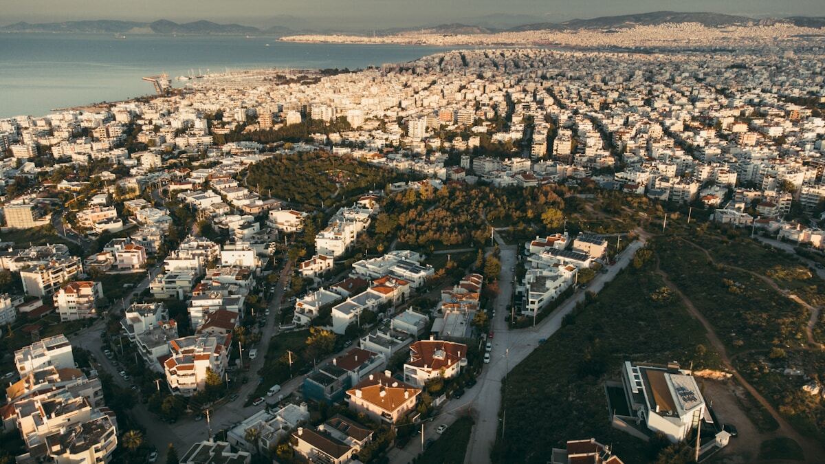 Panorama urbain d'une ville côtière avec des bâtiments et des collines verdoyantes.