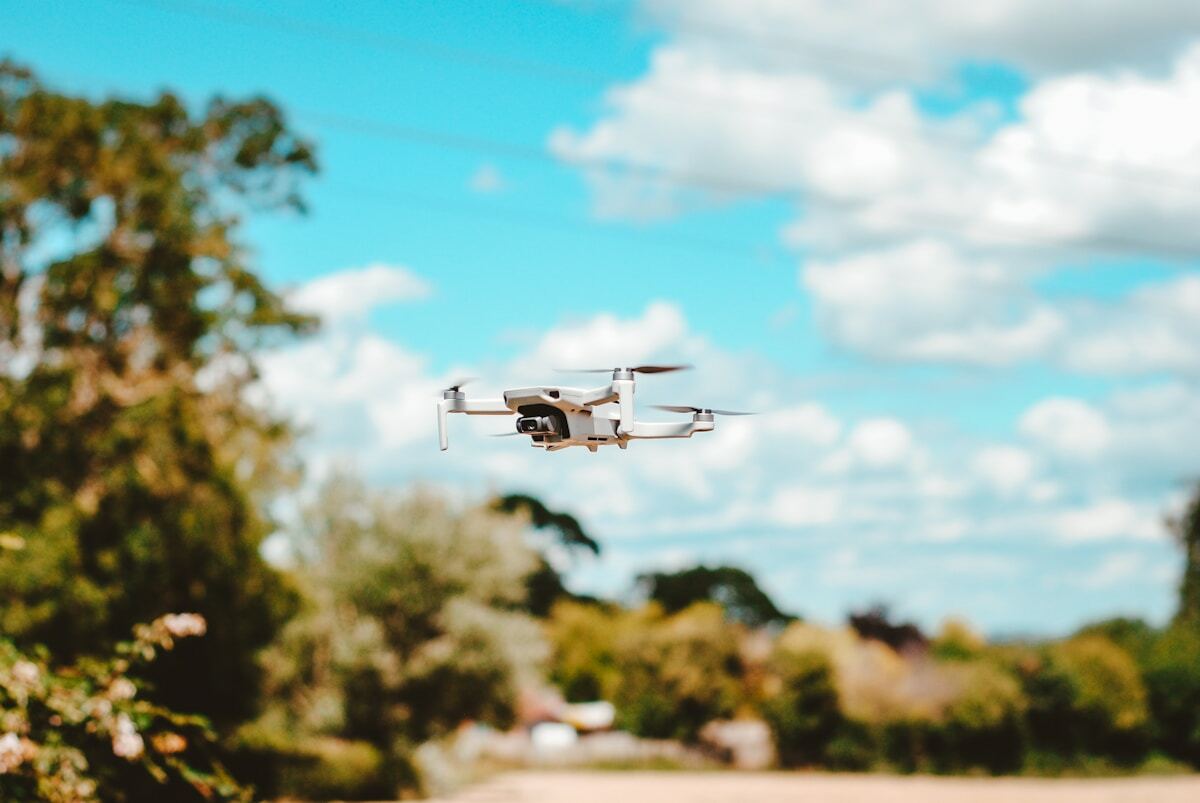 Drone volant dans un paysage verdoyant sous un ciel nuageux.